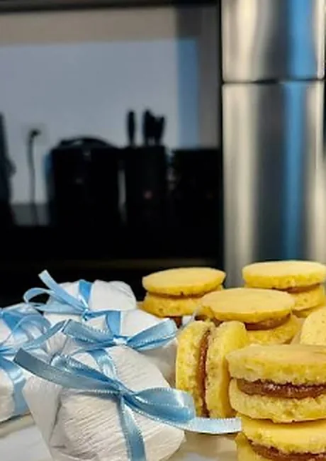 Bem-casados recheados e outros embalados com fita azul, na cozinha